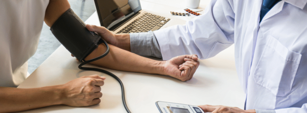 Doctor measuring a patient’s blood pressure at a clinic desk with a laptop, illustrating healthcare branding tips that build trust.