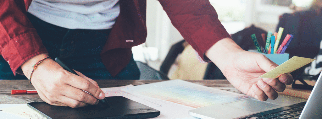 Web designer using a pen tablet and color swatches at a laptop, illustrating web designer ROI.