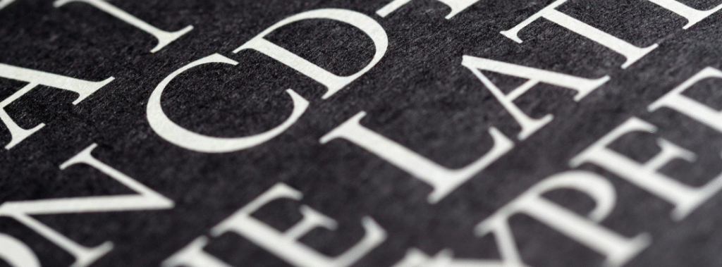 Close up of serif letters printed on dark paper, illustrating outdated branding mistakes in typography.
