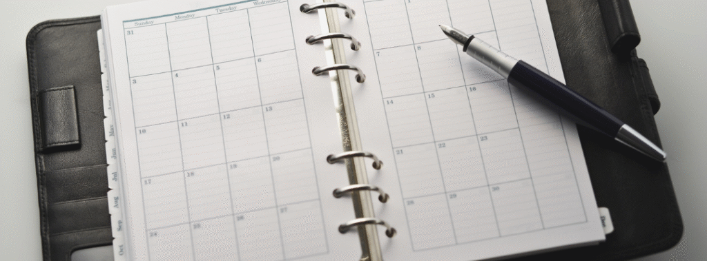 Open monthly planner with pen, representing a graphic design maintenance plan and scheduled ongoing updates.