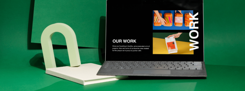 Laptop showing a portfolio page against a green backdrop, designer updating a brand style guide template.