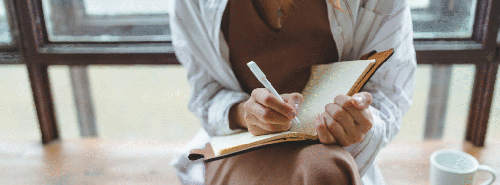 Designer organizing a marketing materials checklist on a laptop with print samples and social templates on the desk.