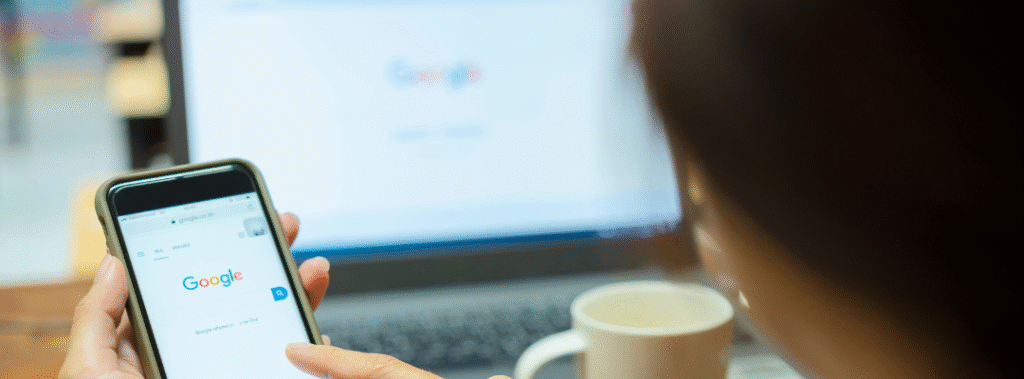 A business owner working on their phone and laptop, optimizing their Google Business Profile.